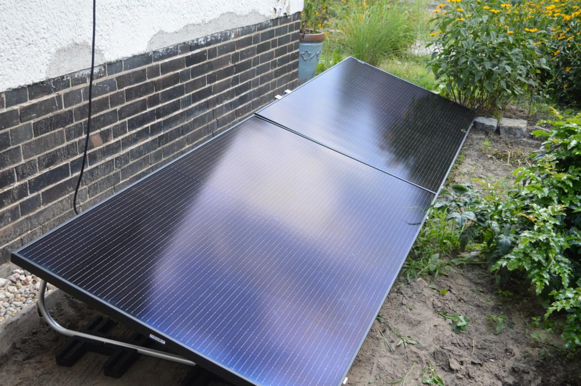 Ein Balkonkraftwerk mit zwei Solarmodulen ist im Garten aufgestellt.